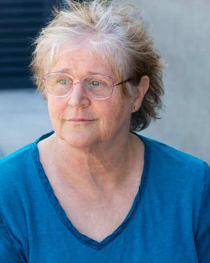 Lois wearing wire rimmed glasses with white hair and blue shirt smiling at the camera