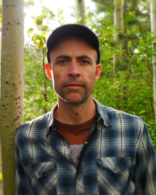 Jason Long in forest wearing baseball cap and plaid shirt